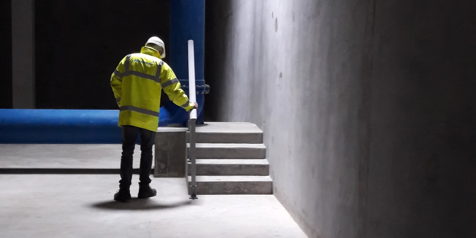 An engineer in high-visibility clothing inspecting a service reservoir inlet